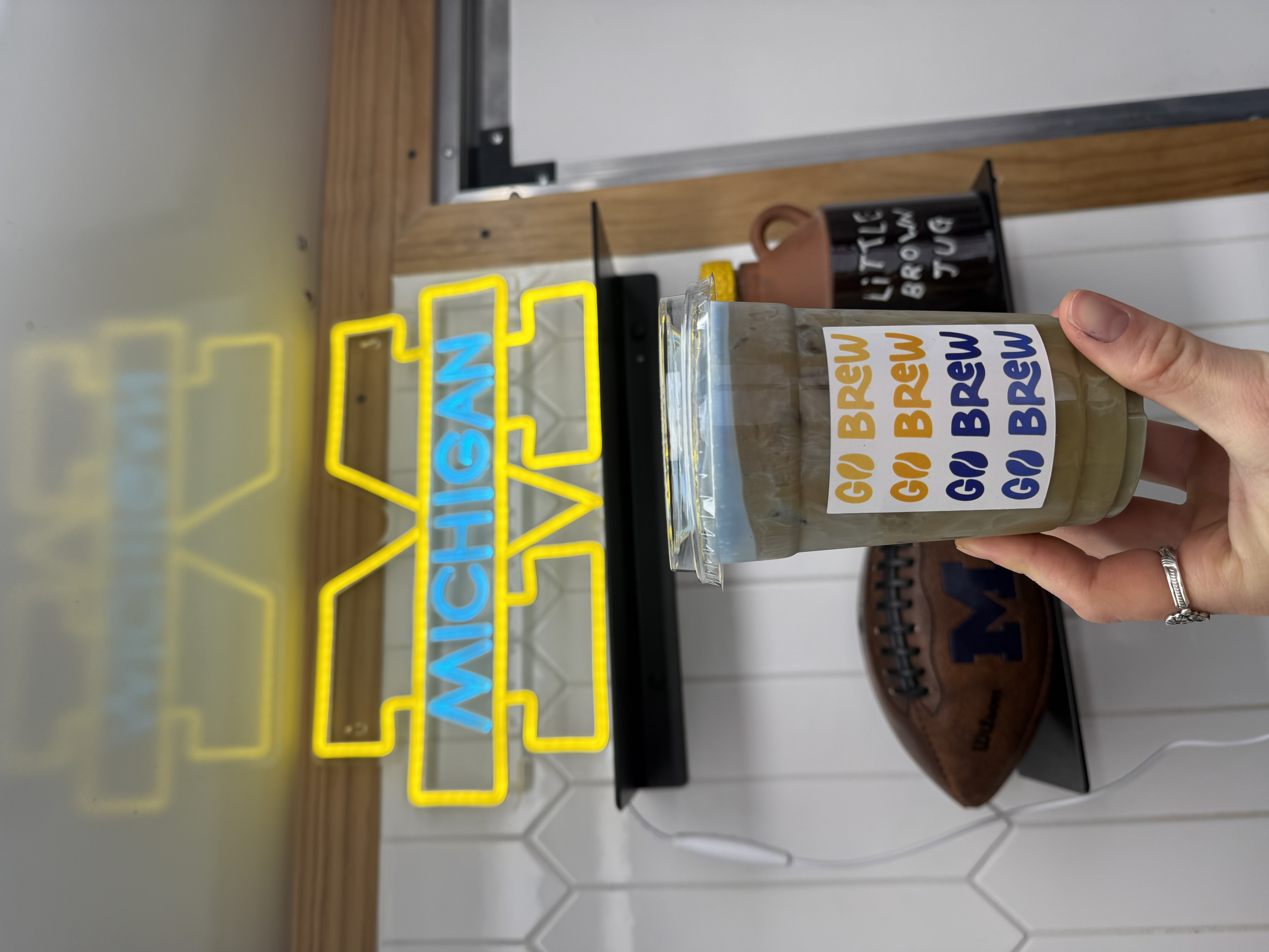Iced Go Brew drink held in front of a Michigan sign